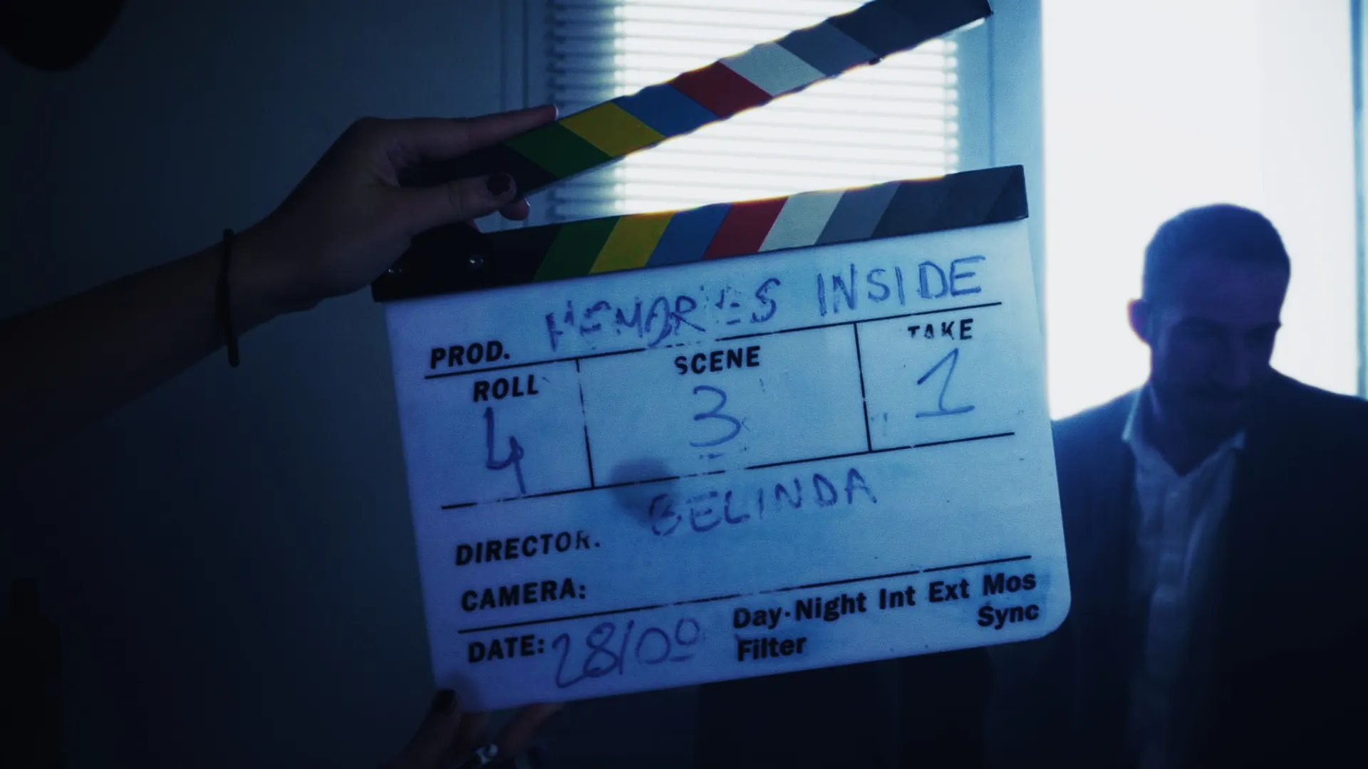 Clap de cinéma tenu devant l'objectif sur un tournage, lumière bleue de fenêtre