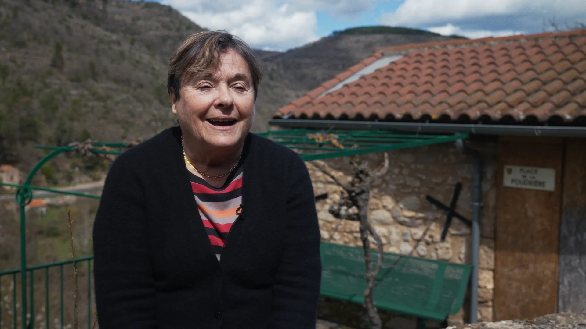 Femme souriante interviewée en extérieur devant un village de montagne