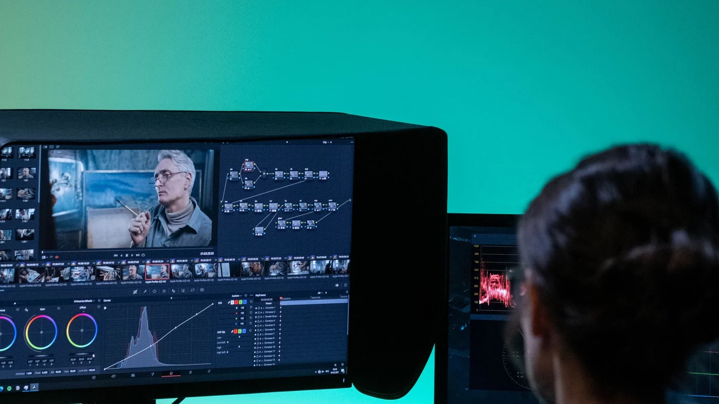 Poste d’étalonnage vu par-dessus l’épaule : écran de montage avec roues colorimétriques et moniteur de scopes