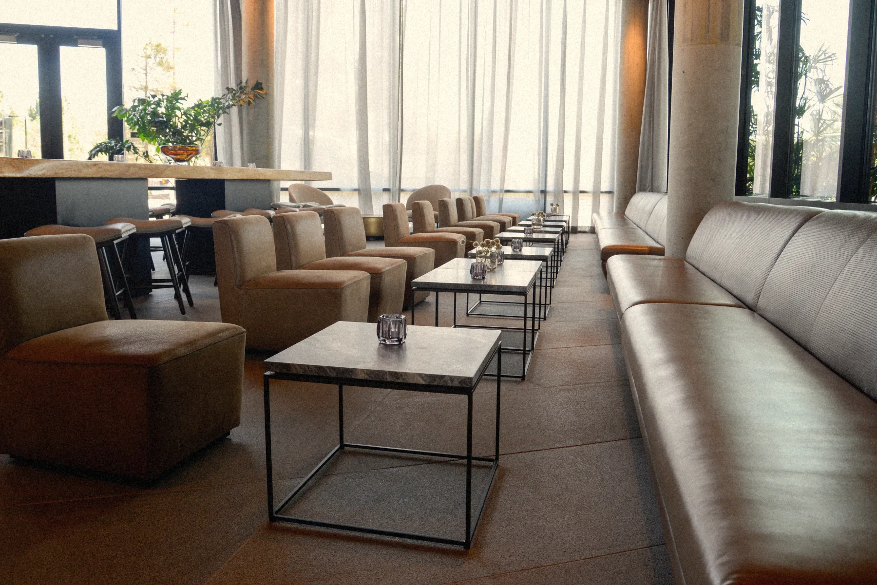 Banquettes de cuir et tables de marbre le long des voilages