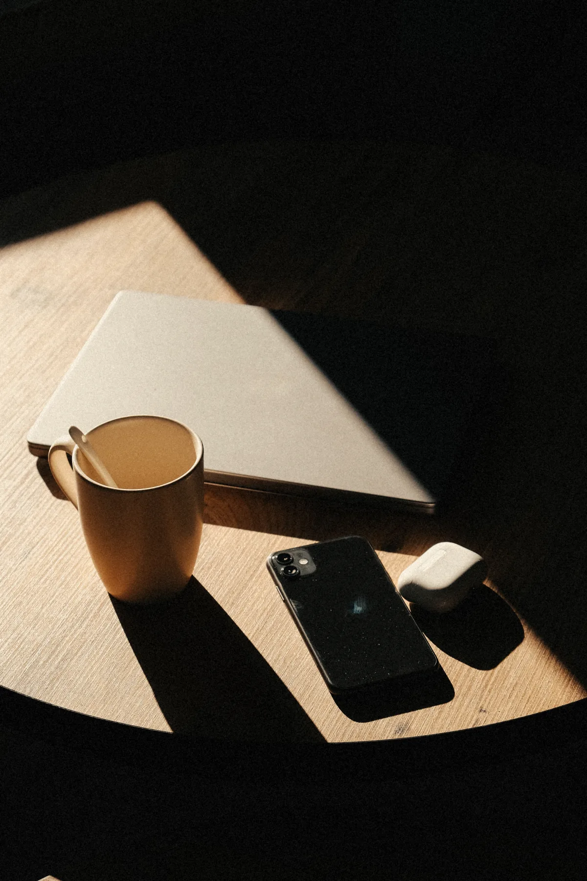 Ordinateur portable refermé et tasse dans un rai de lumière